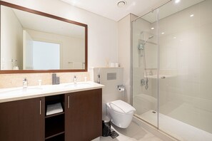A modern bathroom with a glass-enclosed shower, a large mirror, and a dual sink vanity.