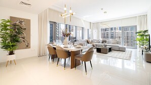 A modern living room with a dining area, large windows, and a city view. - 3Br + Maid Close To Burj Khalifa Dubai Mall (Dubai)