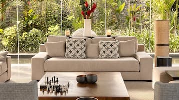 Un salon moderne avec un canapé beige, des coussins à motifs, une table basse en bois et un jeu d’échecs.