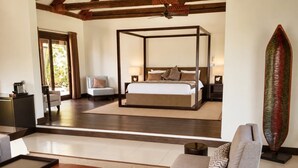 Un dormitorio moderno con cama con dosel, un área de descanso con sofá y mesa de centro, y vistas al exterior.