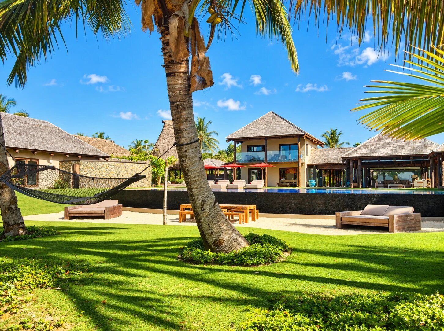 Un complexe hôtelier doté de plusieurs bungalows sur pilotis, d’une piscine et d’un hamac.