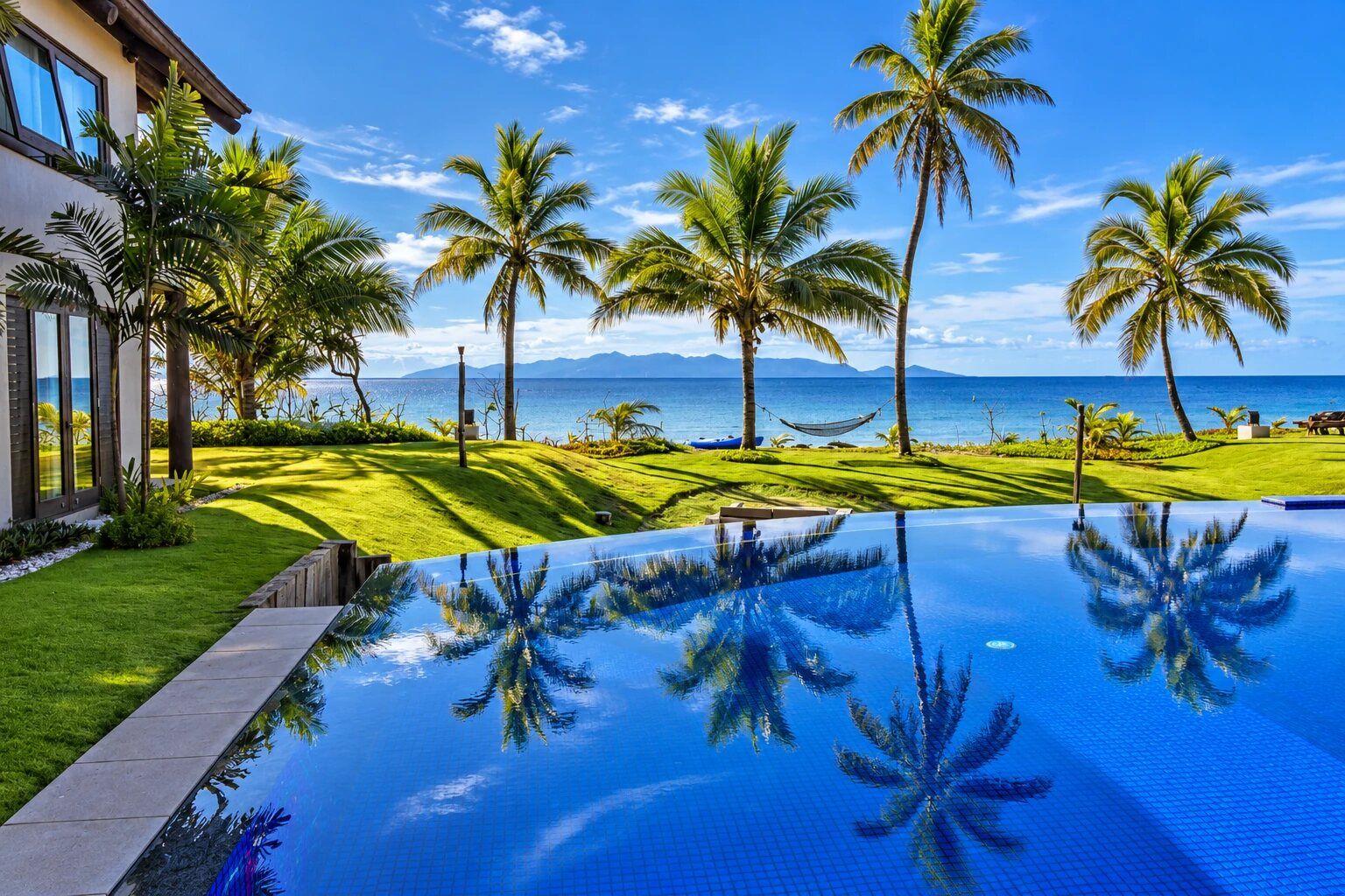 Ein Pool mit freiem Blick auf den Ozean und Palmen.