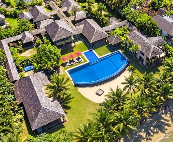 A resort with multiple bungalow-style buildings, a central swimming pool, and lush tropical landscaping.