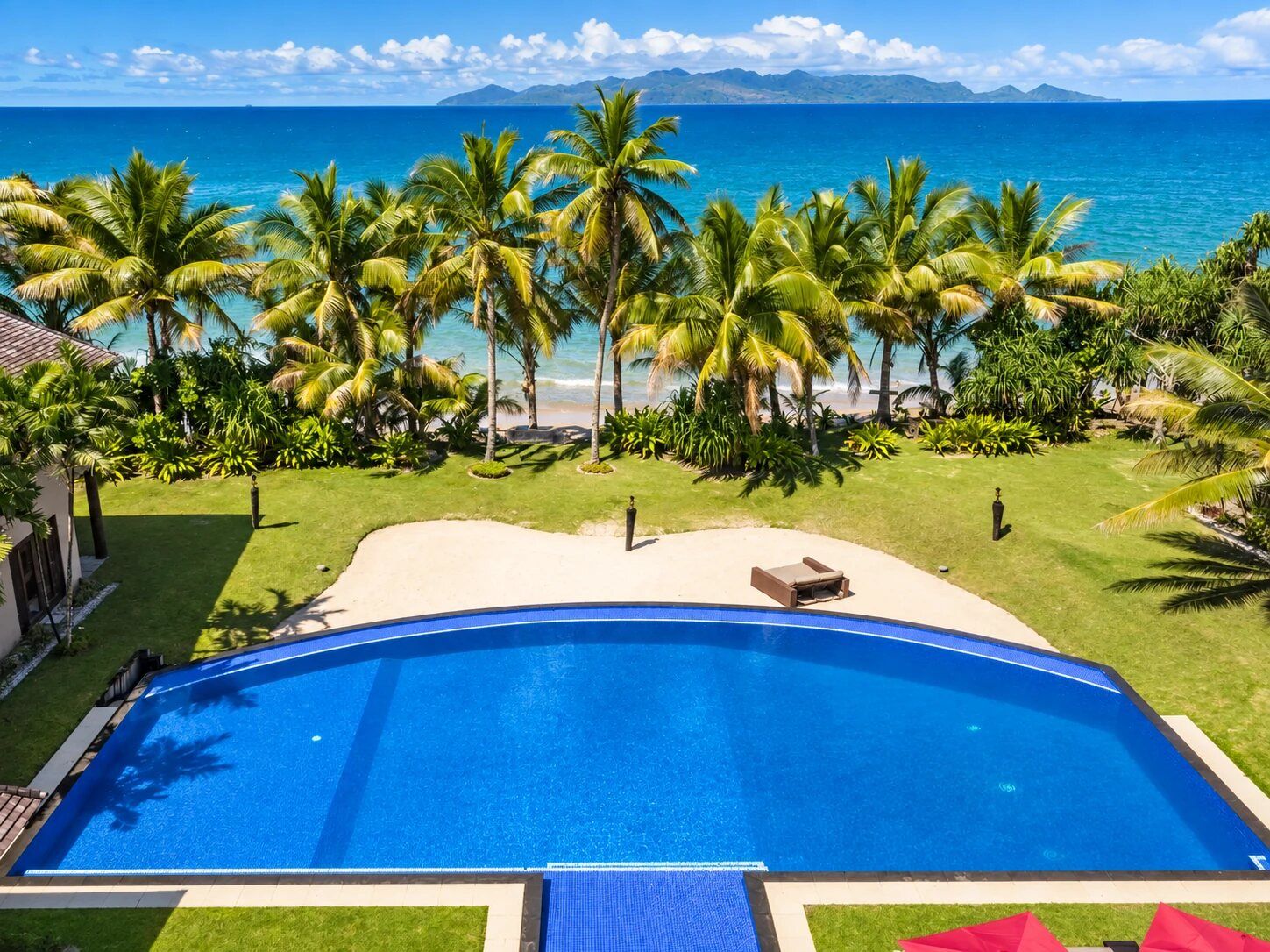 Une piscine avec vue sur l’océan et les palmiers.