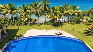 Une piscine avec vue sur l’océan et les palmiers.