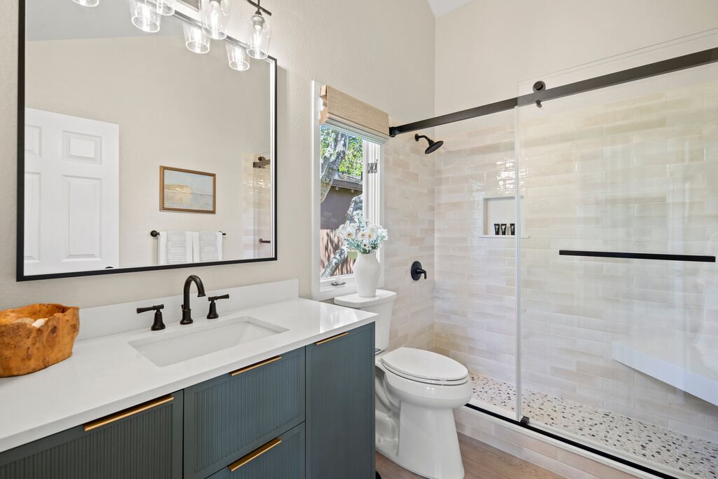 A modern bathroom with a large mirror, white sink, and a glass shower enclosure.