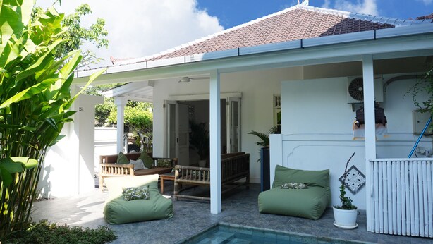 A covered outdoor area with a pool, seating, and potted plants. - Villa The White House Seminyak (Legian)