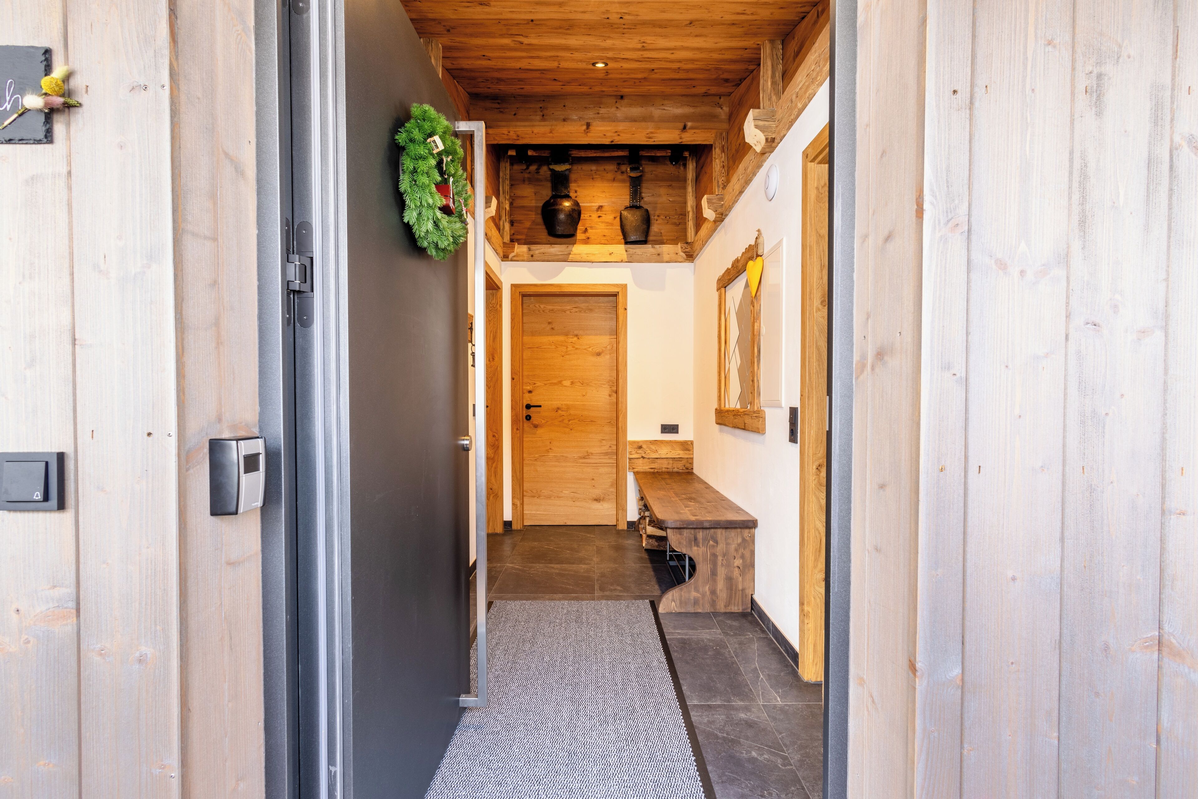 A wooden interior hallway with a door, a bench, and a wall-mounted shelf.
