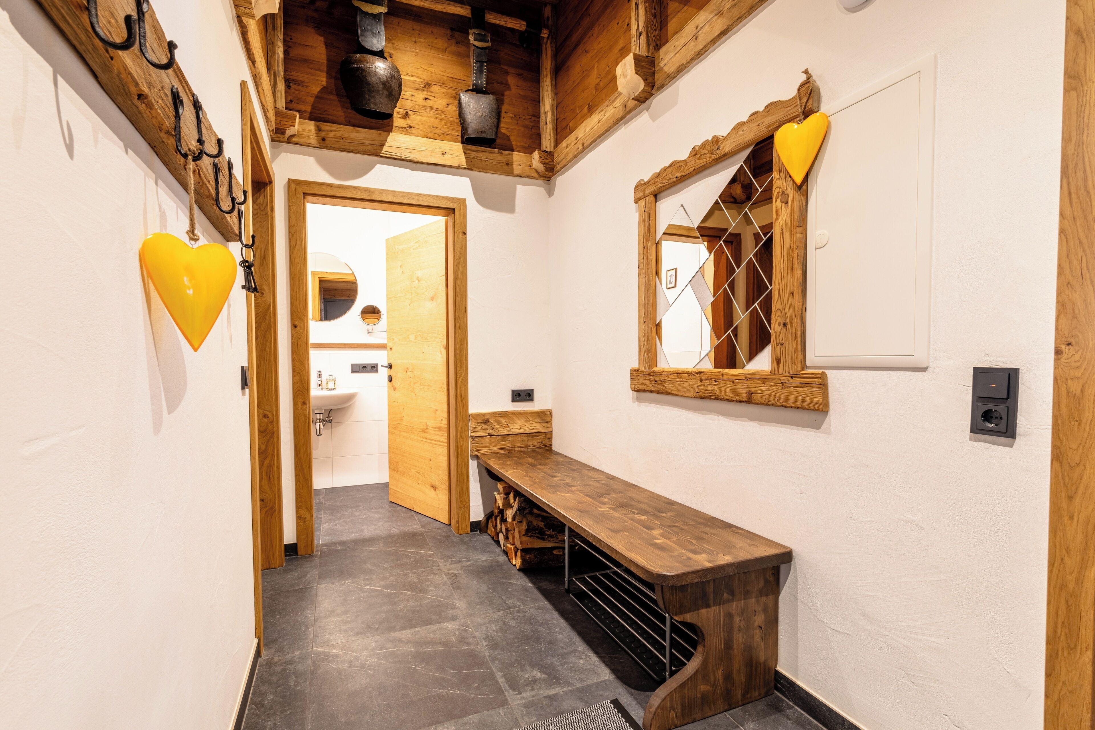 Un pasillo con un banco de madera, un adorno con forma de corazón y una ventana con diseño de rombos.