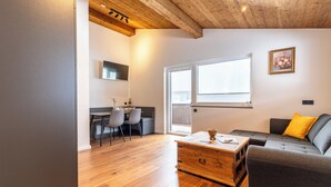 A modern living room with a wooden coffee table, grey sofa, and a dining area with chairs and a table. - Appartement Hoamatgfüh (Saalbach)