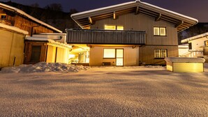A modern two-story house with a balcony, a garage, and a driveway covered in snow. - Appartement Hoamatgfüh (Saalbach)