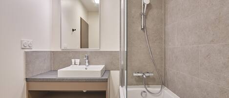 A modern bathroom with a white sink, mirror, and shower.