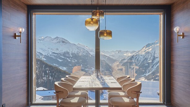 A dining area with a table set for six, facing a large window with a mountain view. - Résidence Odalys L'Ecrin Blanc (La Rosiere)