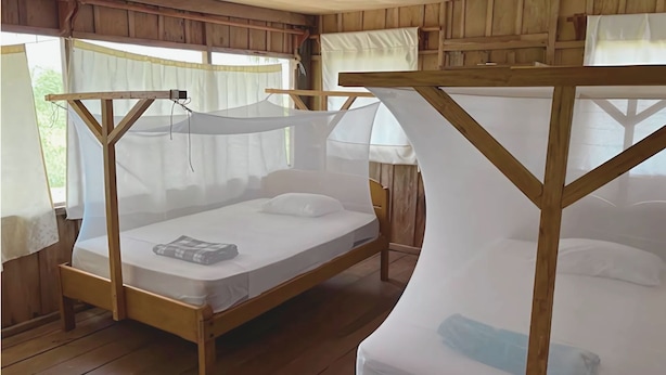 A wooden bed with a mosquito net and a mattress on the floor. - Pacaya Samiria Experience  (Iquitos)