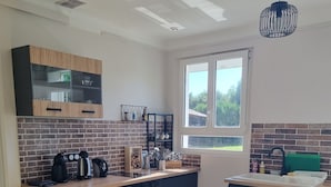 Een moderne keuken met een tegelwand, houten kastjes en een eethoek met een tafel en stoelen.