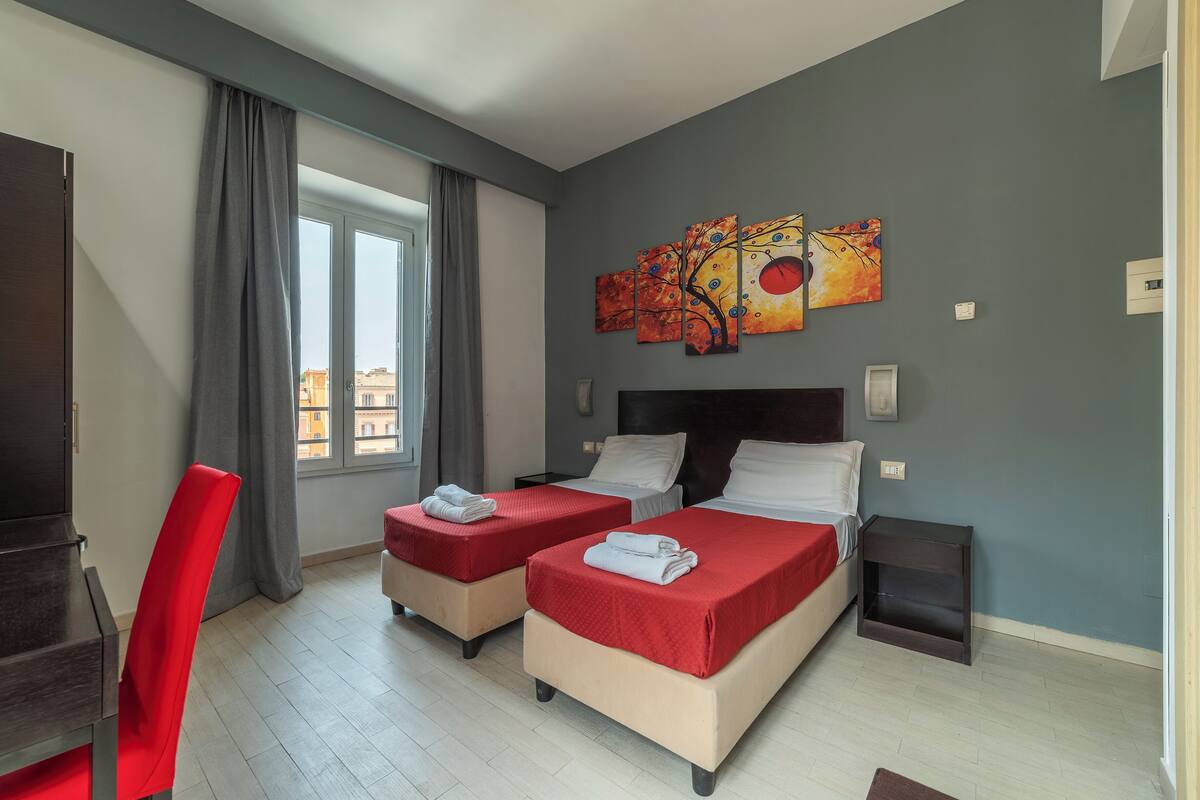A hotel room with two beds, a desk, and a chair.