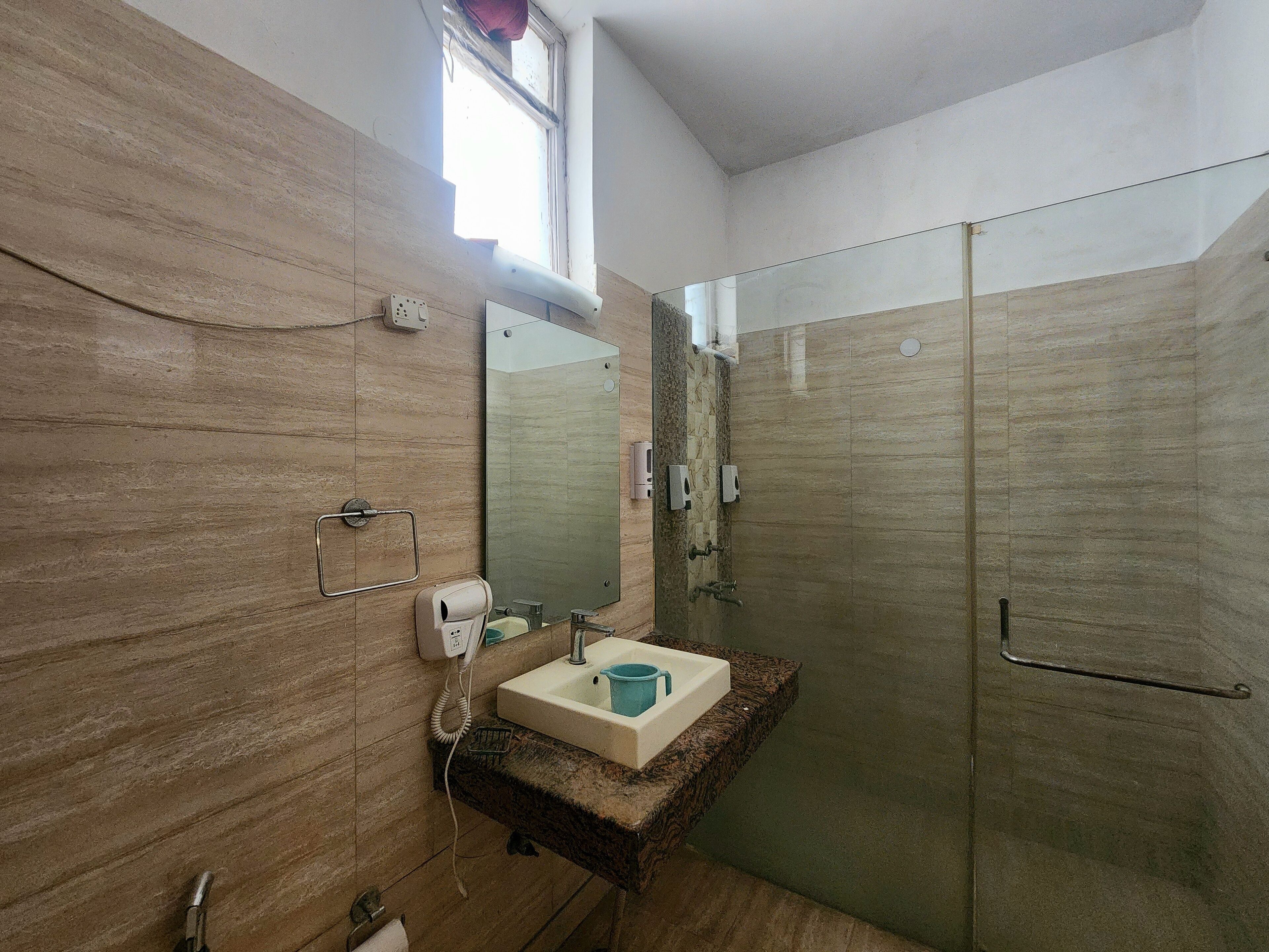 A bathroom with a wooden wall, a sink with a mirror, a towel rack, and a shower area.