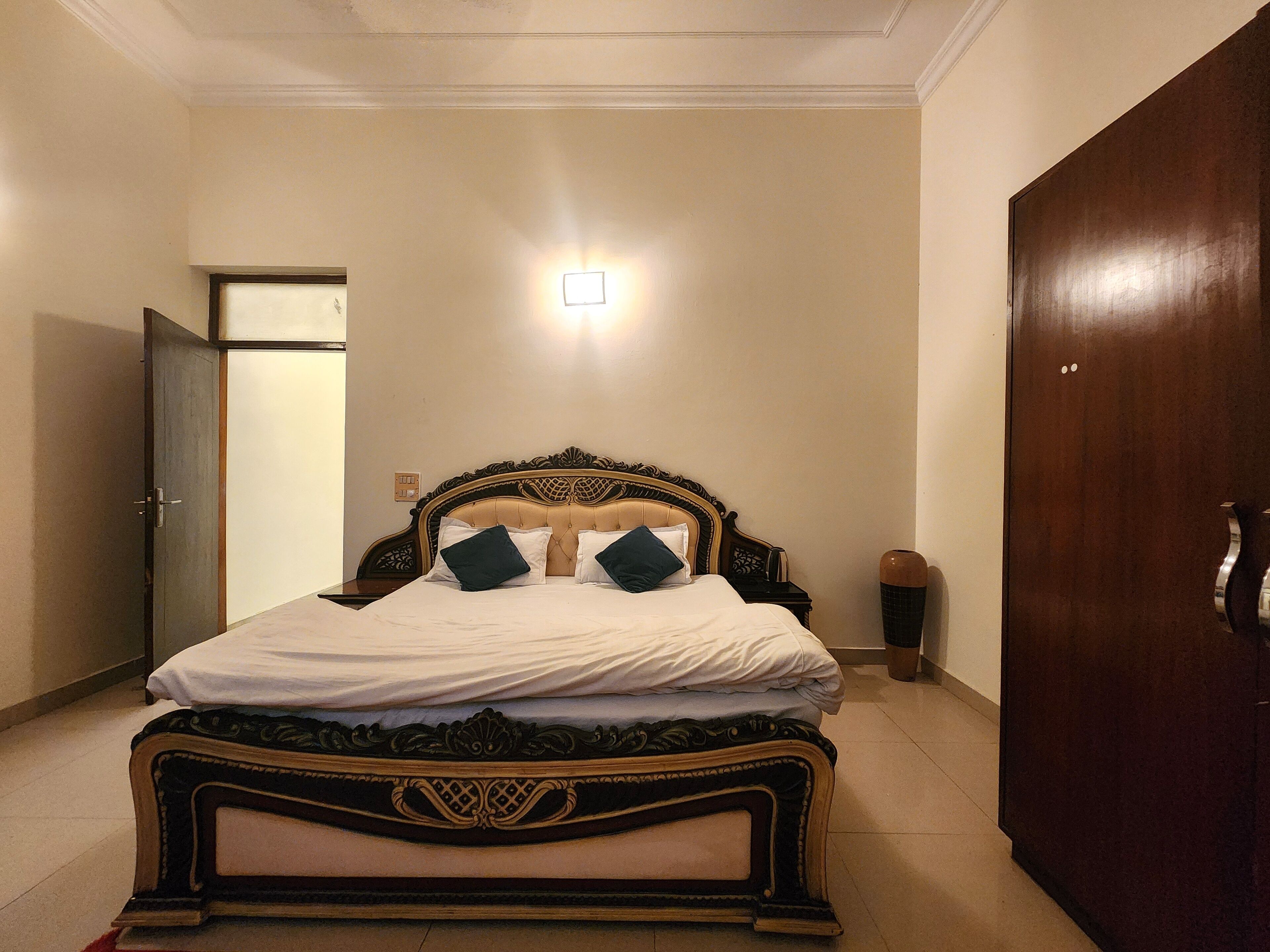 A neatly made bed with a wooden headboard, a bedside table, and a wall-mounted light fixture.