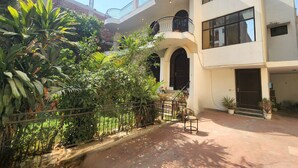 A two-story building with a balcony, a staircase, and a garden area with various plants. - Hotel The Own Stay-Urban Boutique (New Delhi)