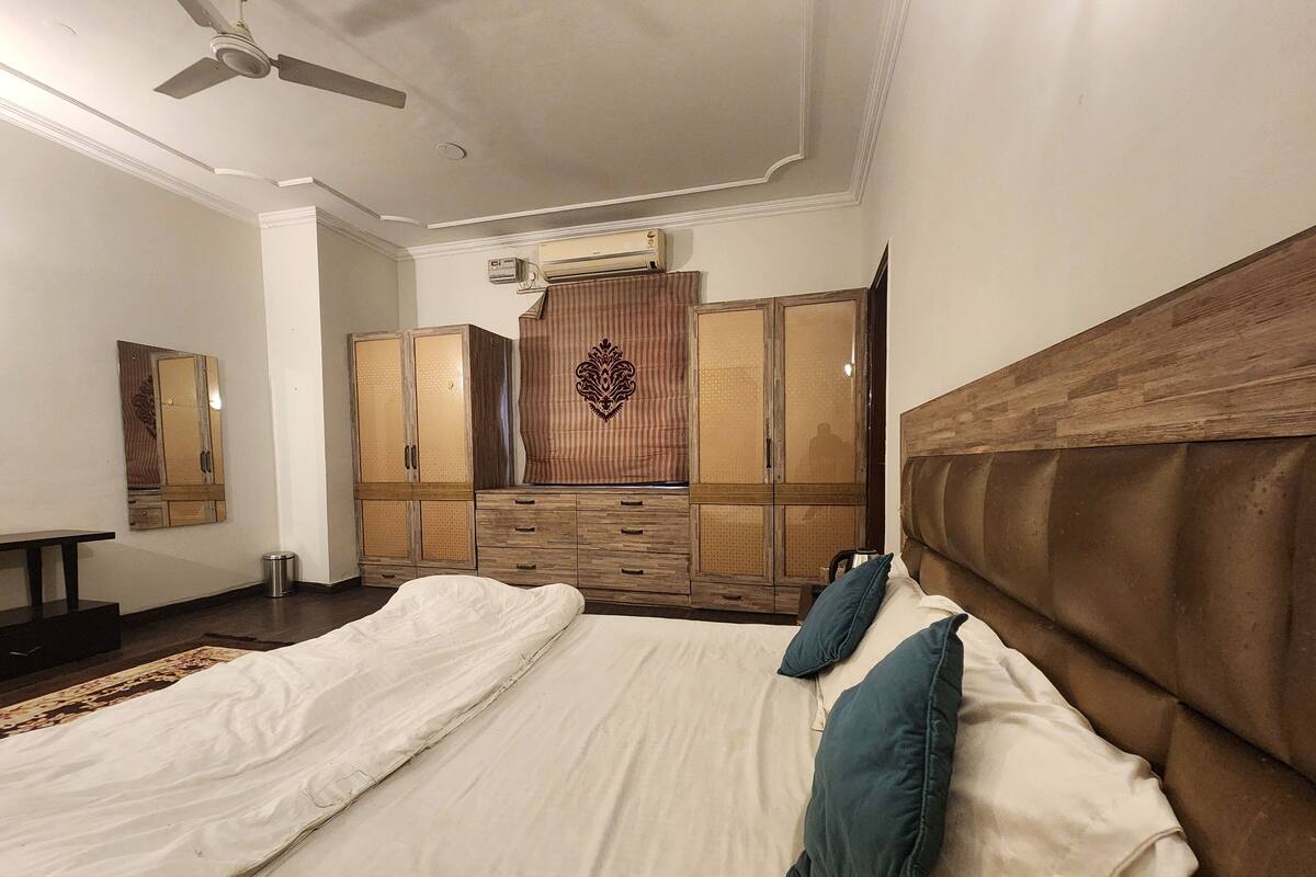 Une chambre à coucher avec un grand lit, une armoire et un ventilateur de plafond.