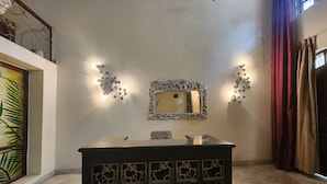 A room with a mirror, decorative wall lights, a patterned cabinet, and a window with curtains. - Hotel The Own Stay-Urban Boutique (New Delhi)