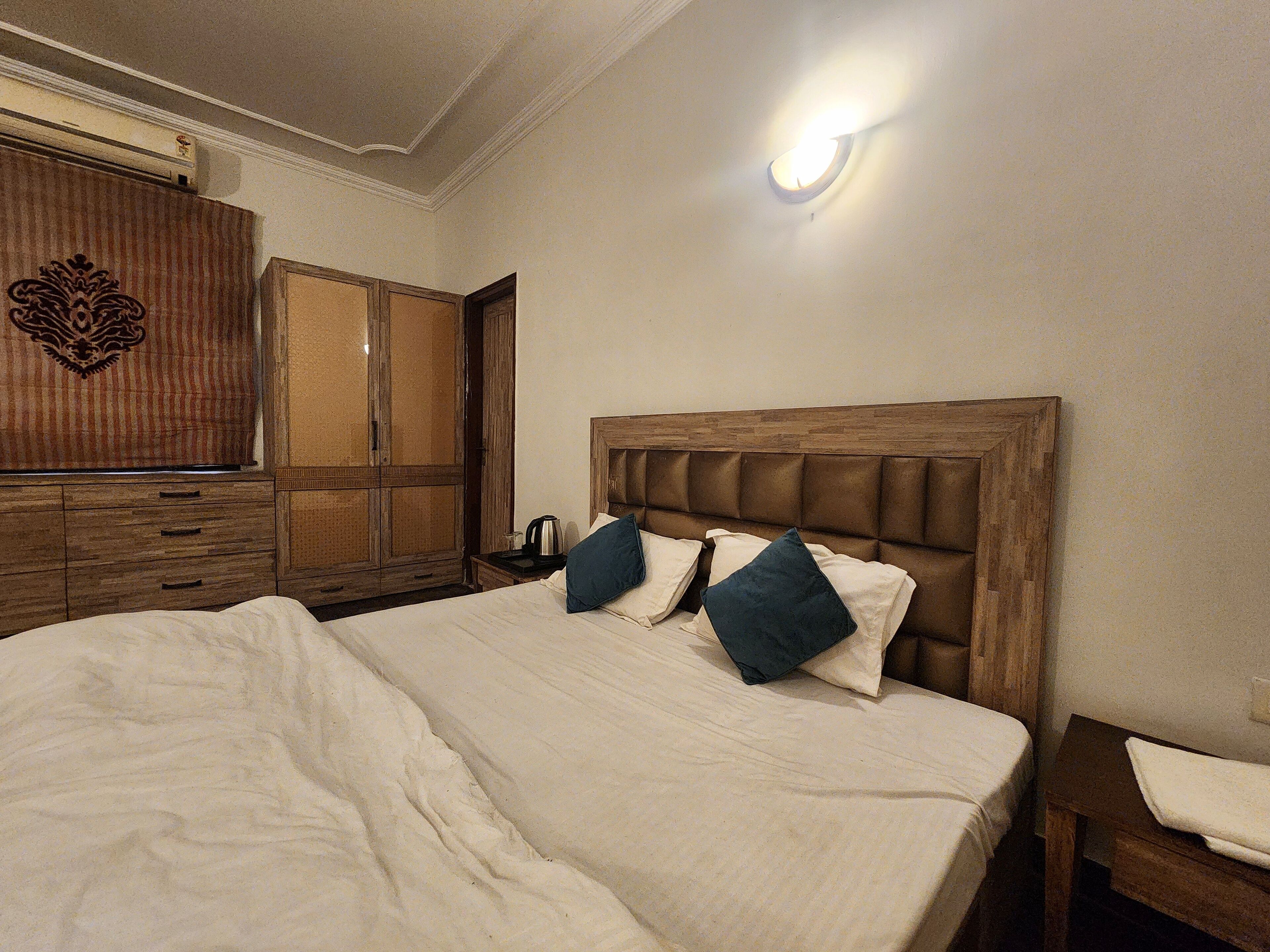 A bedroom with a large bed, wooden headboard, and a nightstand with a lamp.