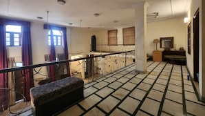 A spacious room with a high ceiling, a patterned floor, and a balcony with a railing. - Hotel The Own Stay-Urban Boutique (New Delhi)