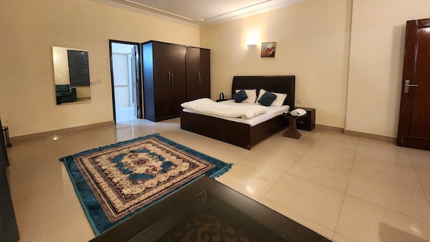 A bedroom with a bed, nightstand, wardrobe, and a large mirror. - Hotel The Own Stay-Urban Boutique (New Delhi)