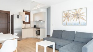 Un salon moderne avec un canapé gris, une table basse blanche et un coin repas comprenant une table et des chaises blanches.
