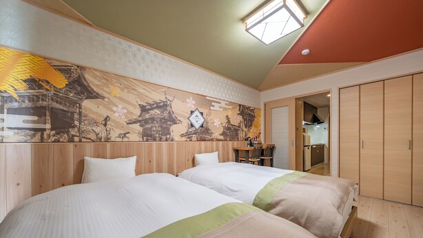 A hotel room with two beds, a dining table, and a kitchen area visible through an open door. - Stay Maison Hida Takayama (Takayama)