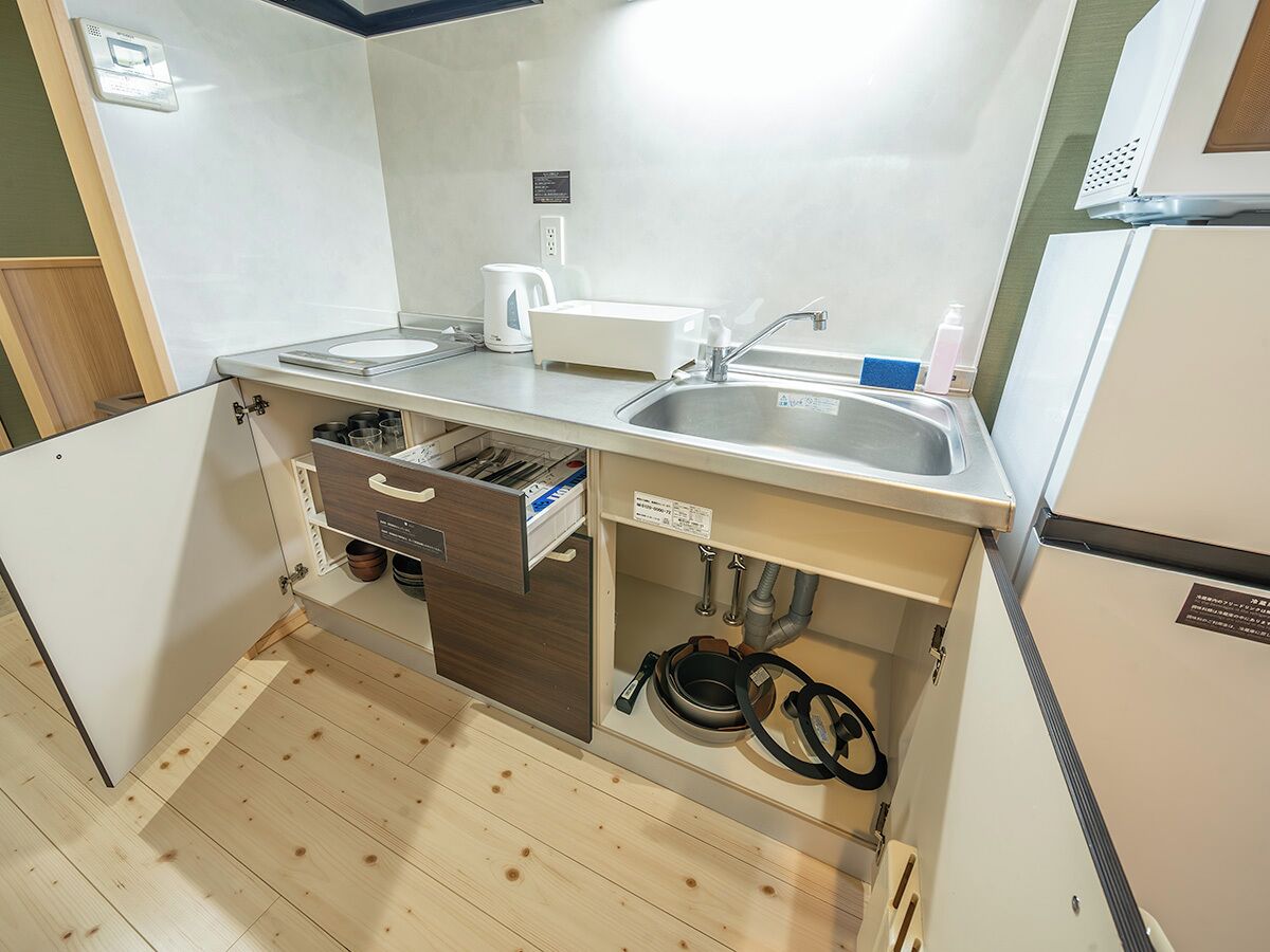 A compact kitchenette with a sink, a coffee maker, and a storage cabinet.