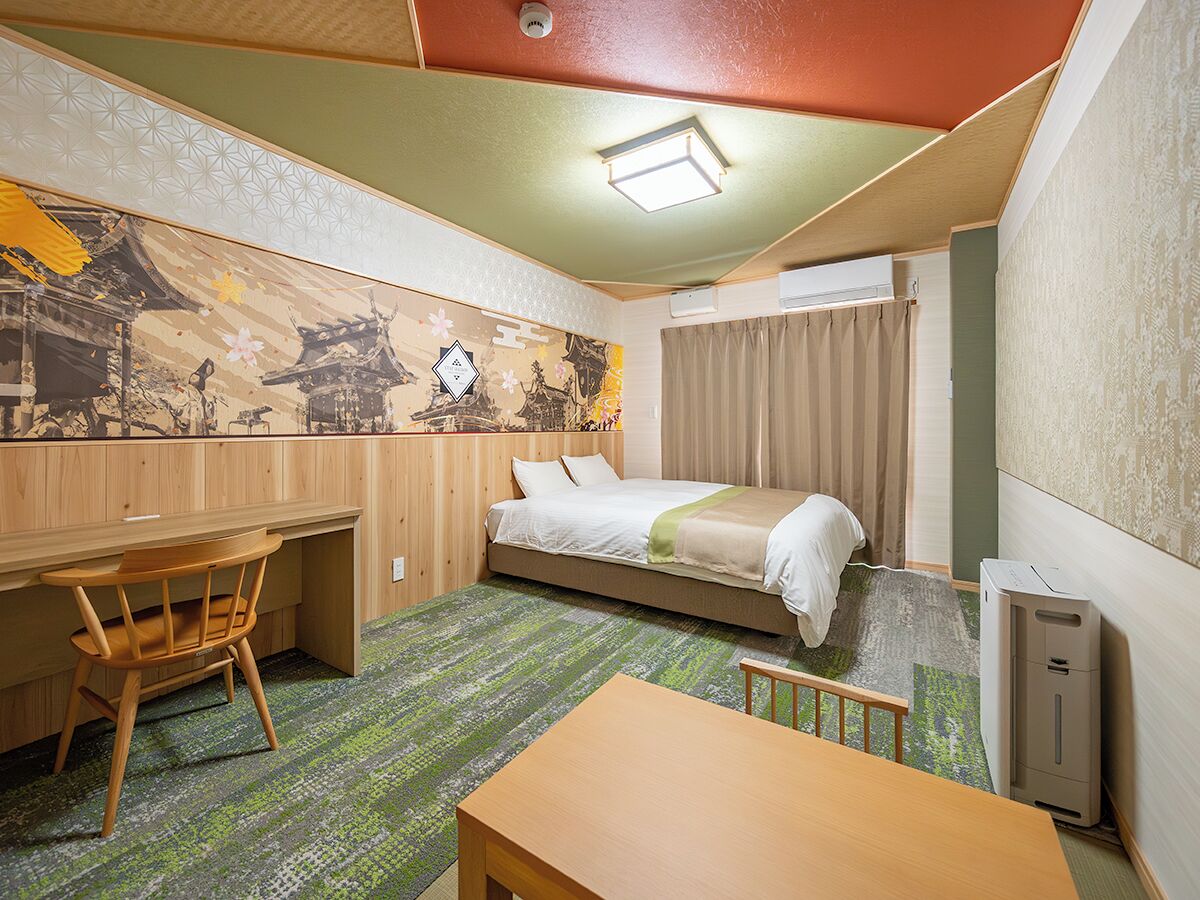 Een kleine hotelkamer met een bed, bureau en stoel.