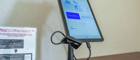A tablet on a stand displaying a check-in interface with QR code scanning instructions.