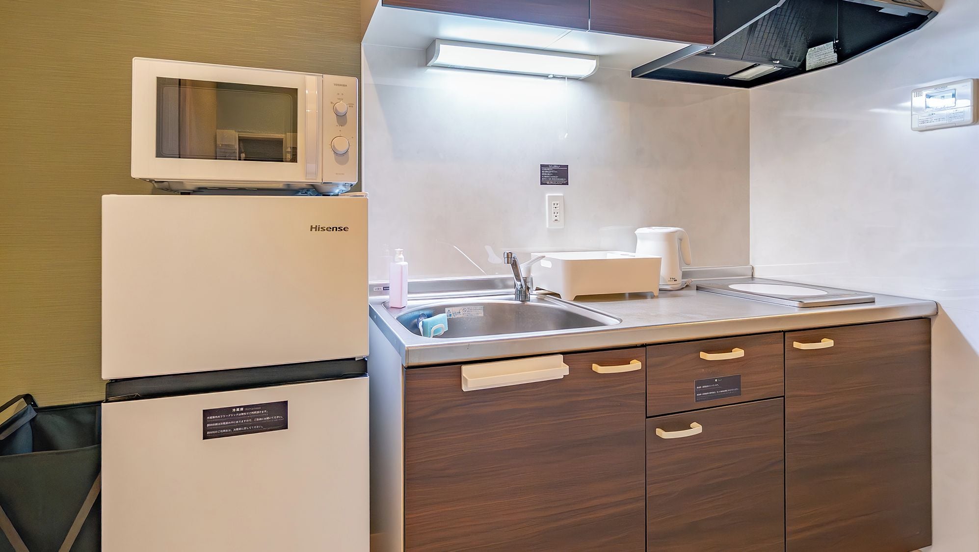 A compact kitchen with a microwave, sink, and a small cabinet.