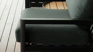 A row of dark-colored sofas with cushions, positioned on a wooden deck with a glass railing, overlooking a green outdoor area. - Waterfront Luxury in Opossum Bay (Opossum Bay)
