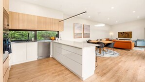 Una cocina moderna con comedor, armarios de madera y vistas a zonas verdes.