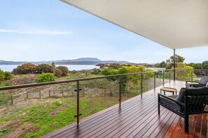 A balcony with a view of the sea and hills, furnished with a sofa and a table.