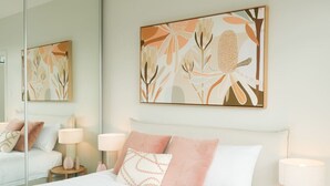 A bedroom with a bed, two bedside lamps, and a large mirror. - Waterfront Luxury in Opossum Bay (Opossum Bay)
