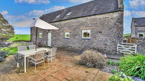 A stone building with a patio, outdoor seating, and a view of the green landscape. - Holiday Home in Ashbourne near Dovedale Trails (Ashbourne)