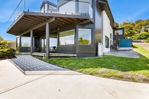 Een modern huis met een overdekte patio, grote ramen en een verzorgd gazon.