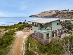 Una casa costera de dos pisos con un amplio balcón y vista al océano.