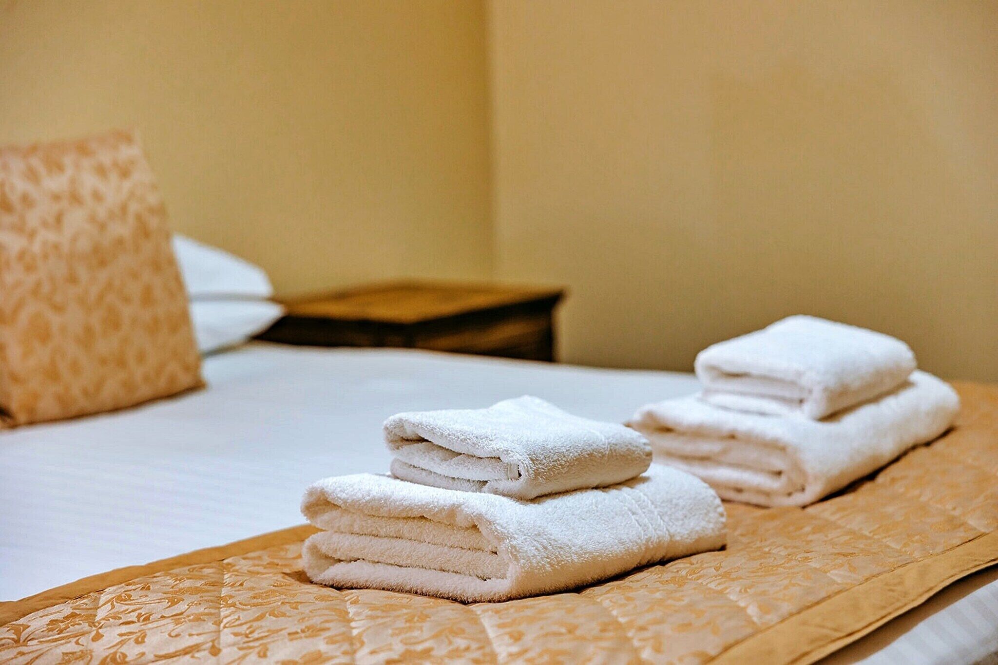 Un lit bien fait, avec des serviettes blanches pliées et une couvre-lit à motifs.