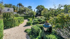 A garden pathway leading to a building with a metal roof, surrounded by various shrubs and plants. - Bellevue House Historic Luxury (Richmond)