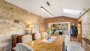A dining area with a wooden table, chairs, and a brick wall. - Bellevue House Historic Luxury (Richmond)