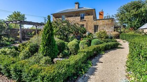 A stone house with a gravel path, surrounded by well-maintained hedges and trees. - Bellevue House Historic Luxury (Richmond)