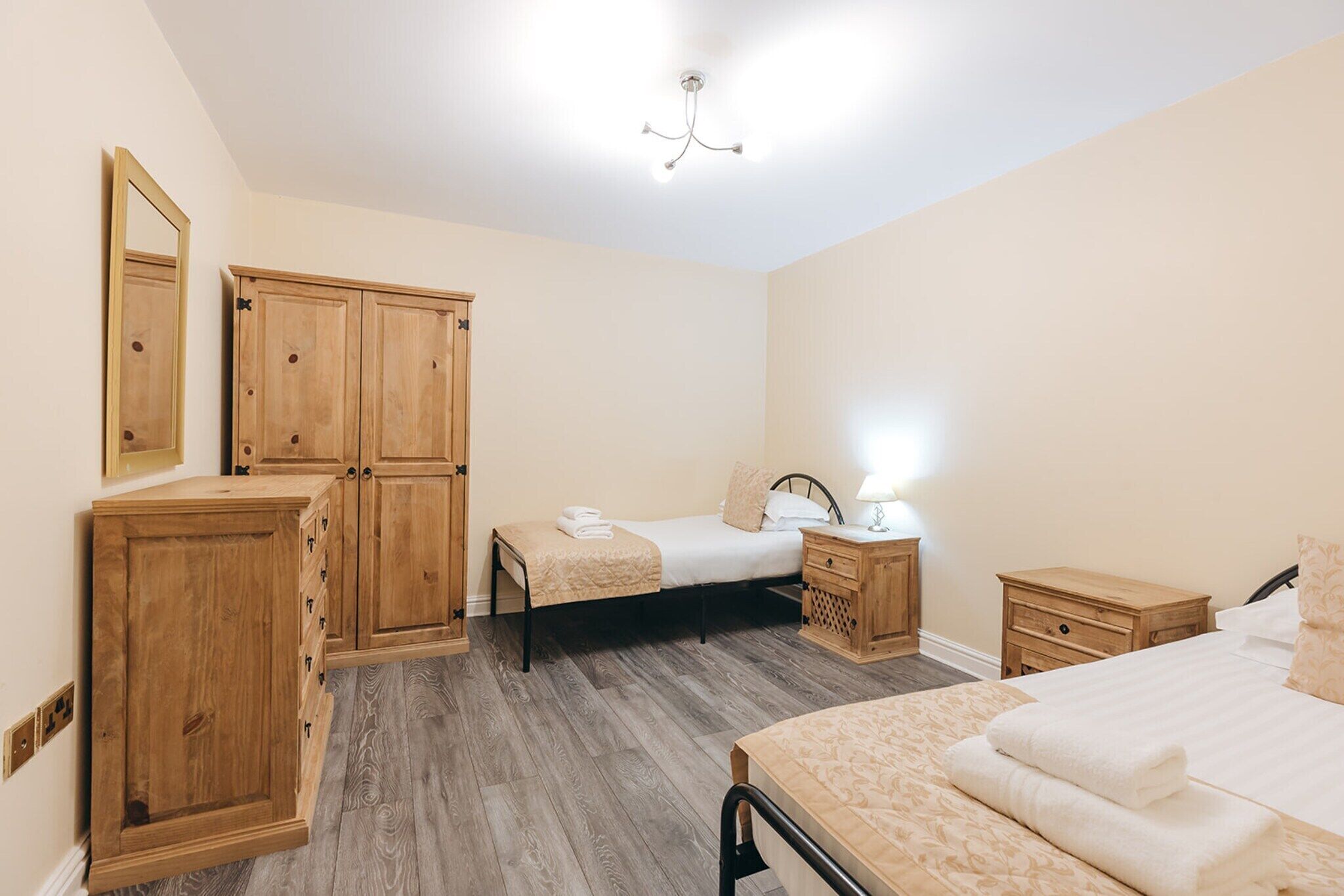 Une chambre à coucher comprenant un lit, des tables de chevet, une armoire et un miroir.