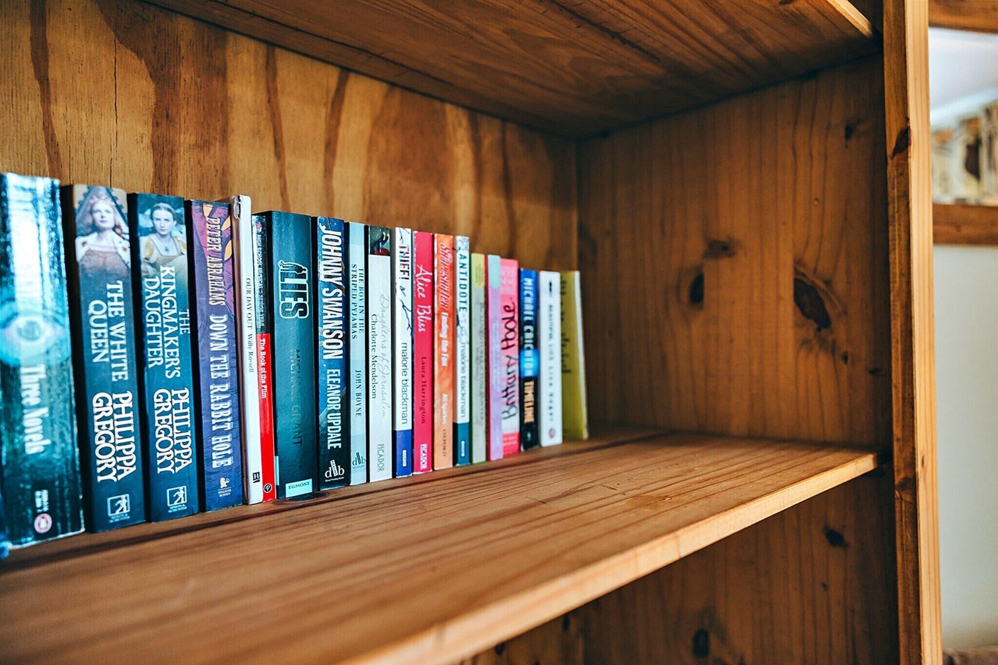 Uma estante de madeira com diversos livros.
