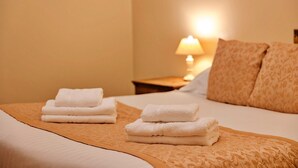 A neatly made bed with folded white towels and a patterned throw blanket.