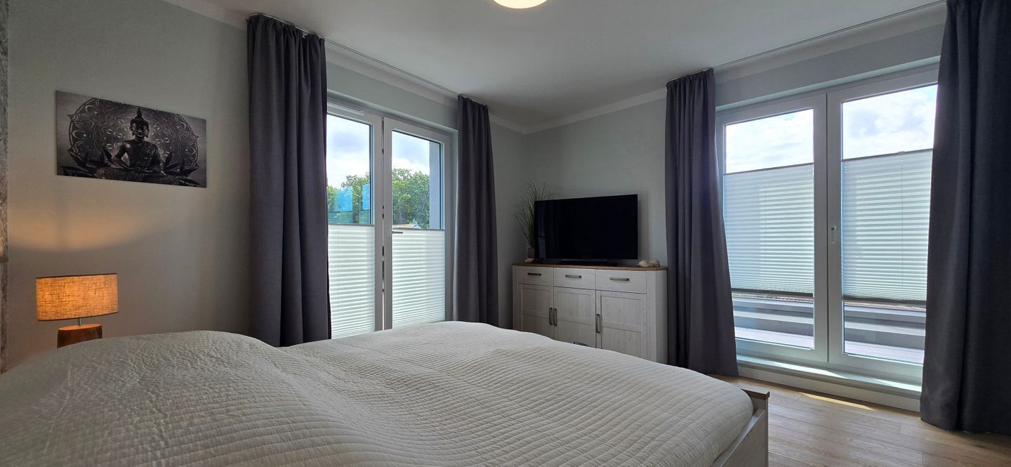 Una camera da letto con un letto grande, una televisione a schermo piatto su un mobile e una finestra con persiane.