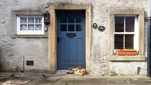 A stone building with a blue door, a small window with shutters, and a flower box on the right. - Cottage in Settle near Yorkshire Dales (Settle)